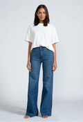 a woman wearing a white t-shirt and high waisted dark wash jeans. white background.