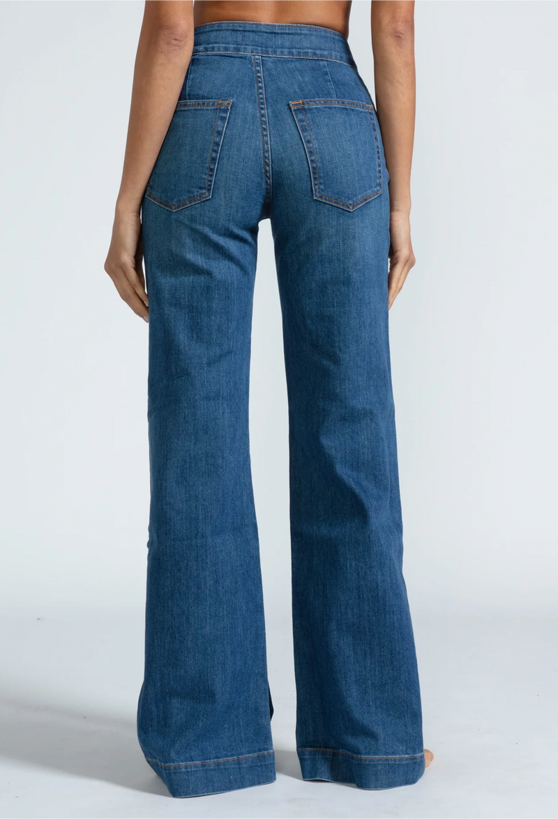 the back of a woman wearing high waisted dark wash jeans. white background.