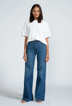 a woman wearing a white t-shirt and high waisted dark wash jeans. white background.