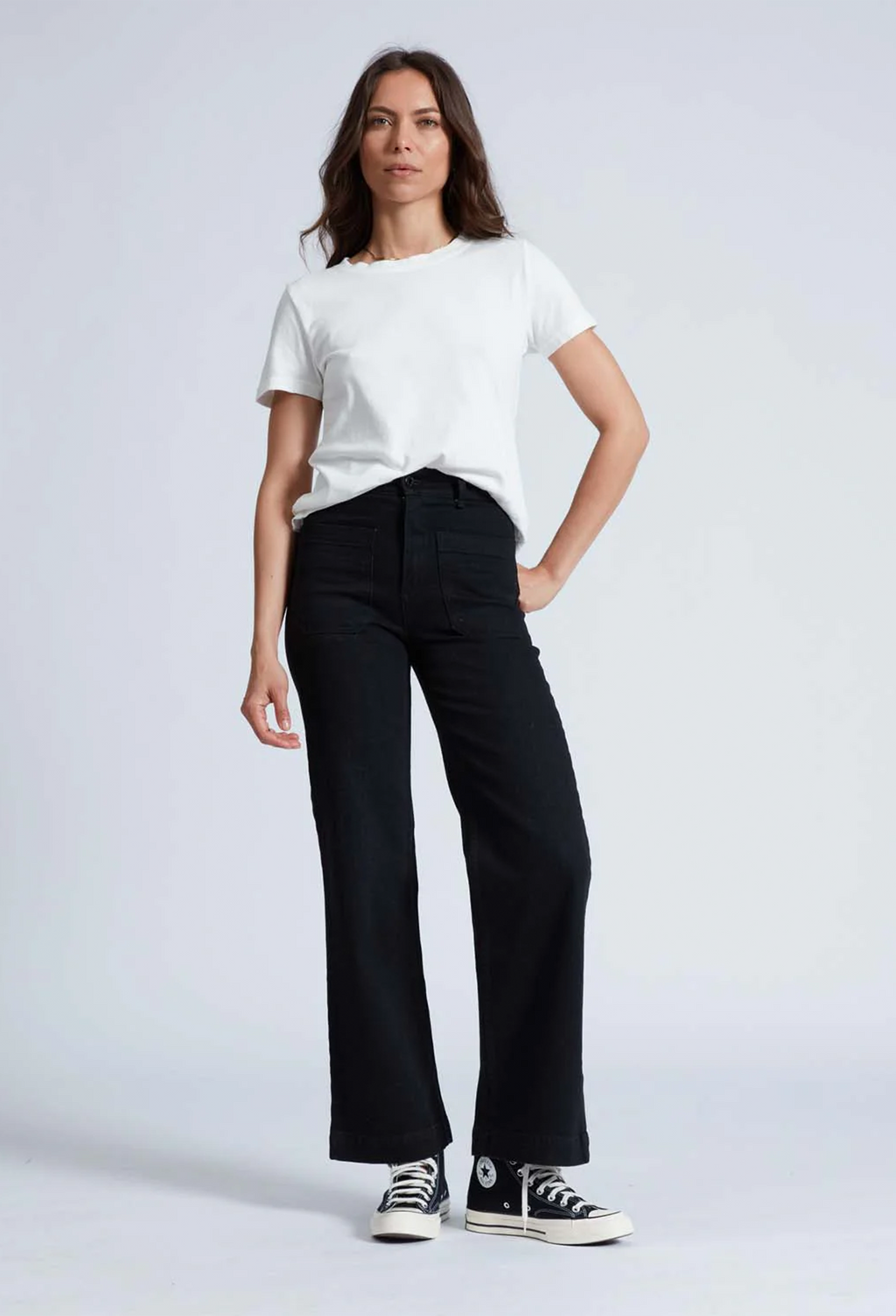 Model wears black high rise wide leg jeans with black sneakers and a short sleeve white t-shirt. 