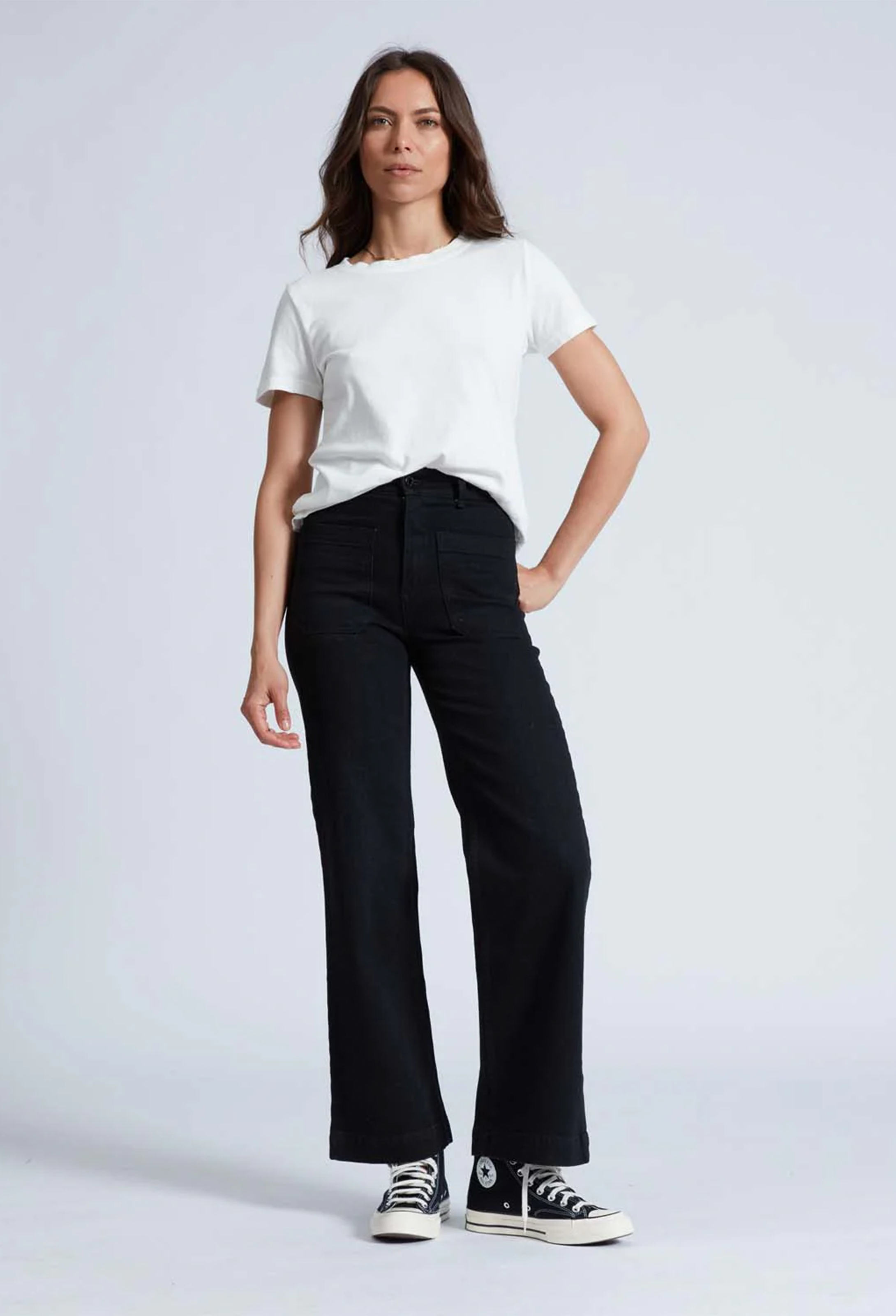 Model wears black high rise wide leg jeans with black sneakers and a short sleeve white t-shirt. 