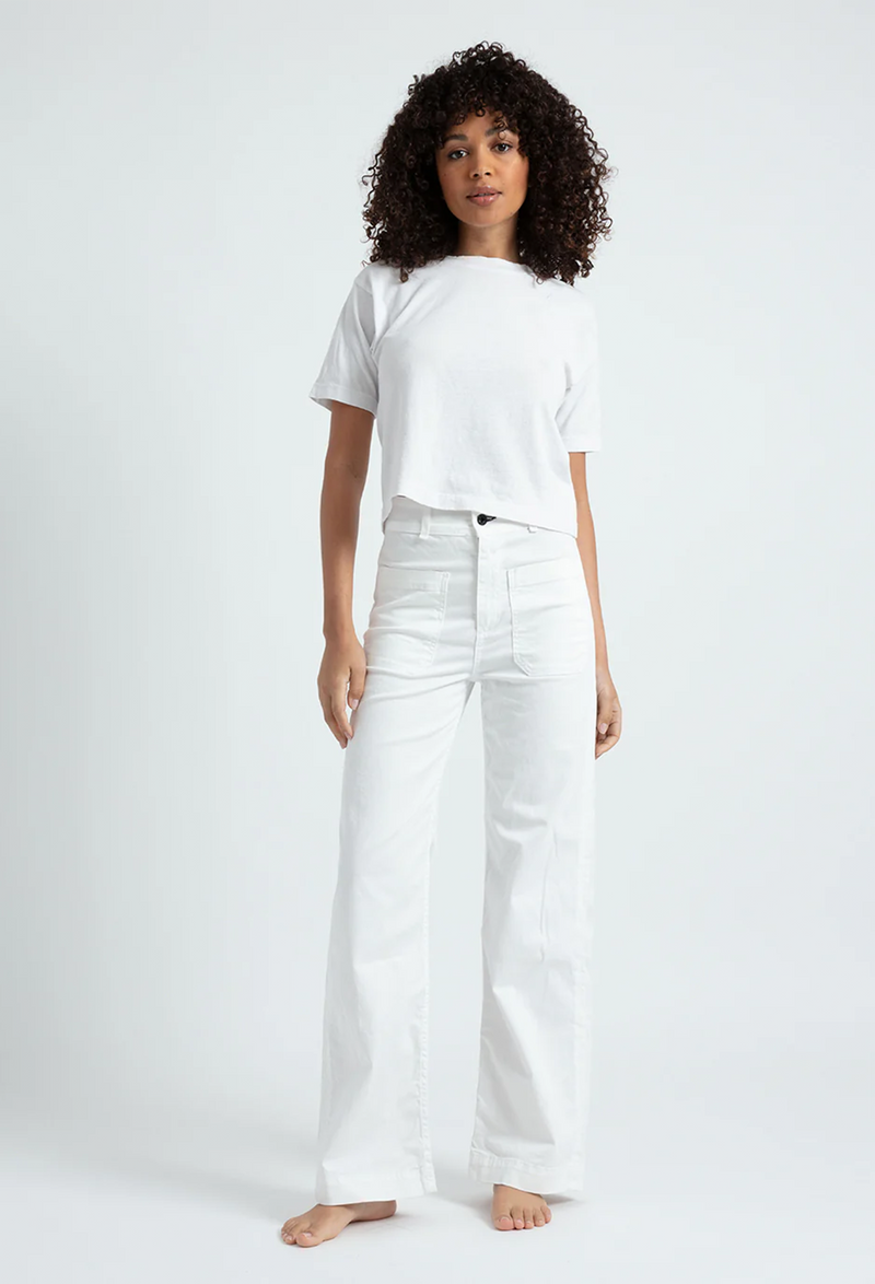 A woman wearing white pants with large front pockets. White background.
