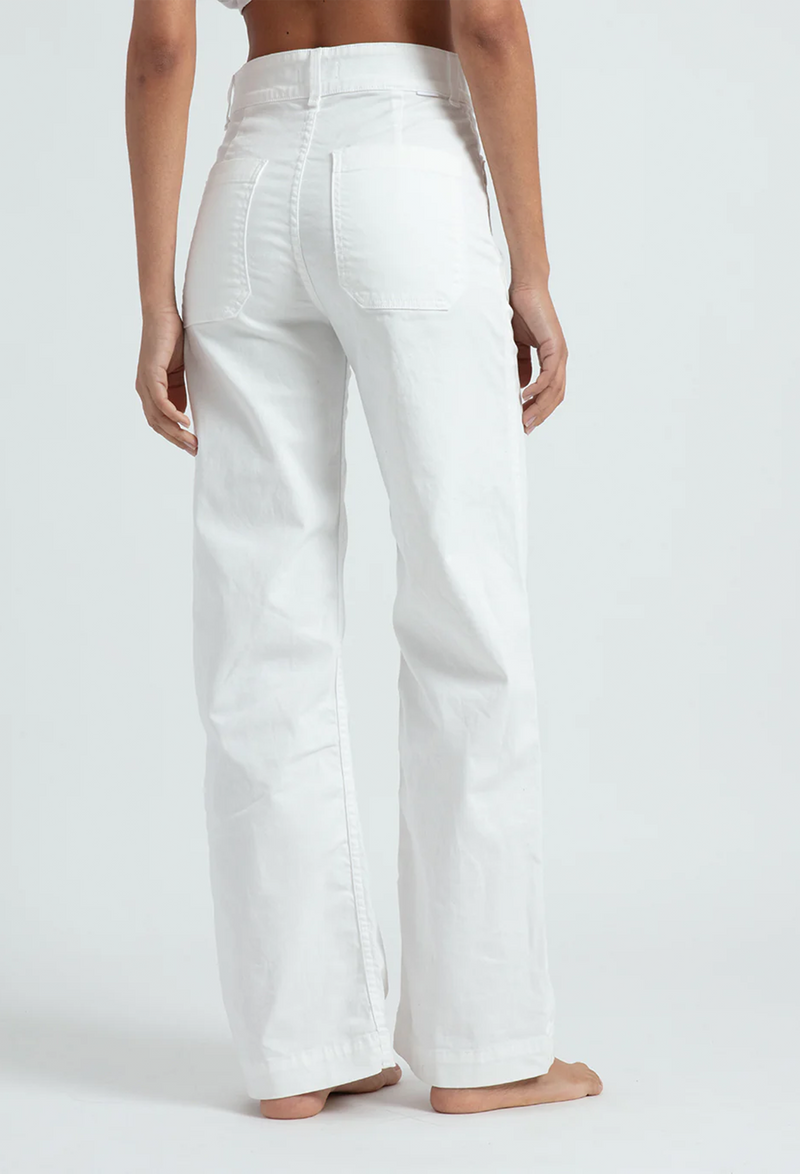 The back of a woman wearing white pants with large pockets. White background.