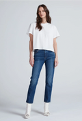A model wearing a white short-sleeve crop top, blue straight-leg jeans, and white pointed boots, standing against a light gray studio background.