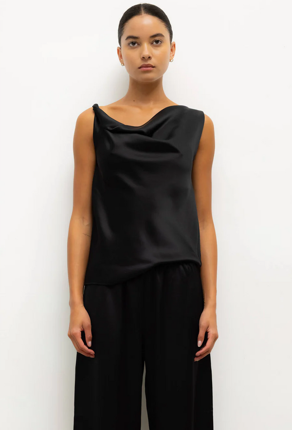 Woman wearing a black sleeveless top and black pants on a white background