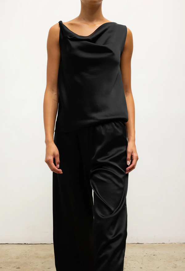 Person wearing a black sleeveless top and pants against a white background