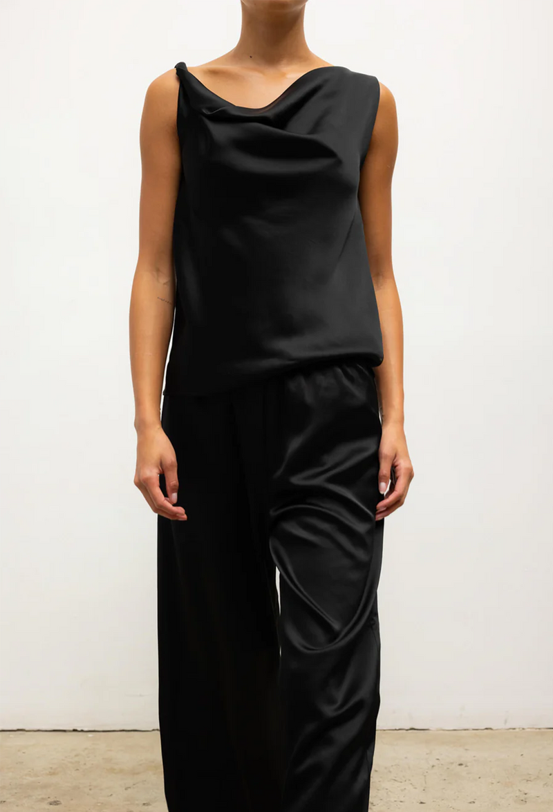 Person wearing a black sleeveless top and pants against a white background