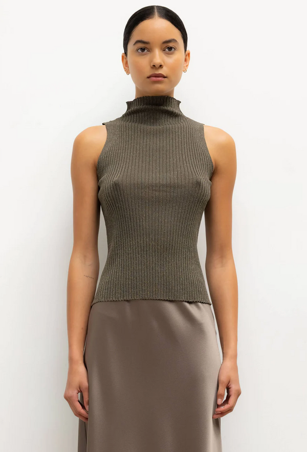 Woman wearing a sleeveless ribbed knit top against a white background