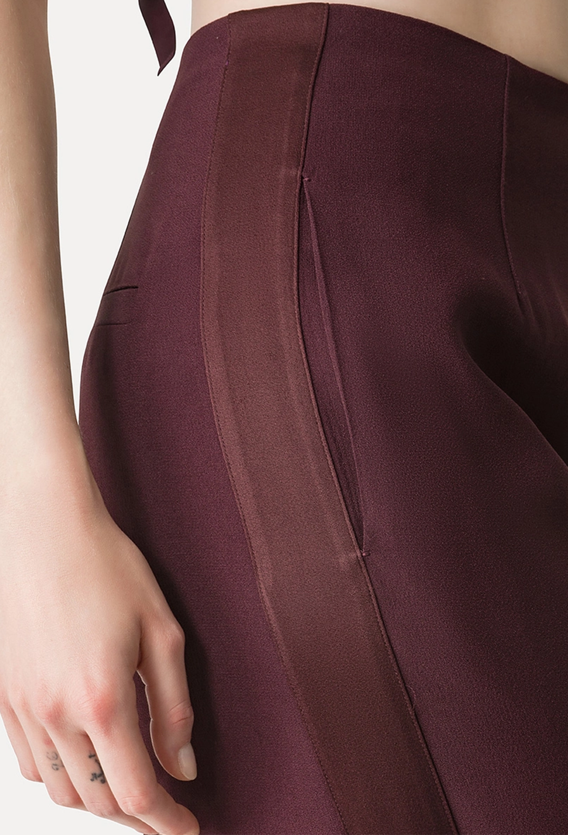Close-up of a person wearing a burgundy Pant with a plain background
