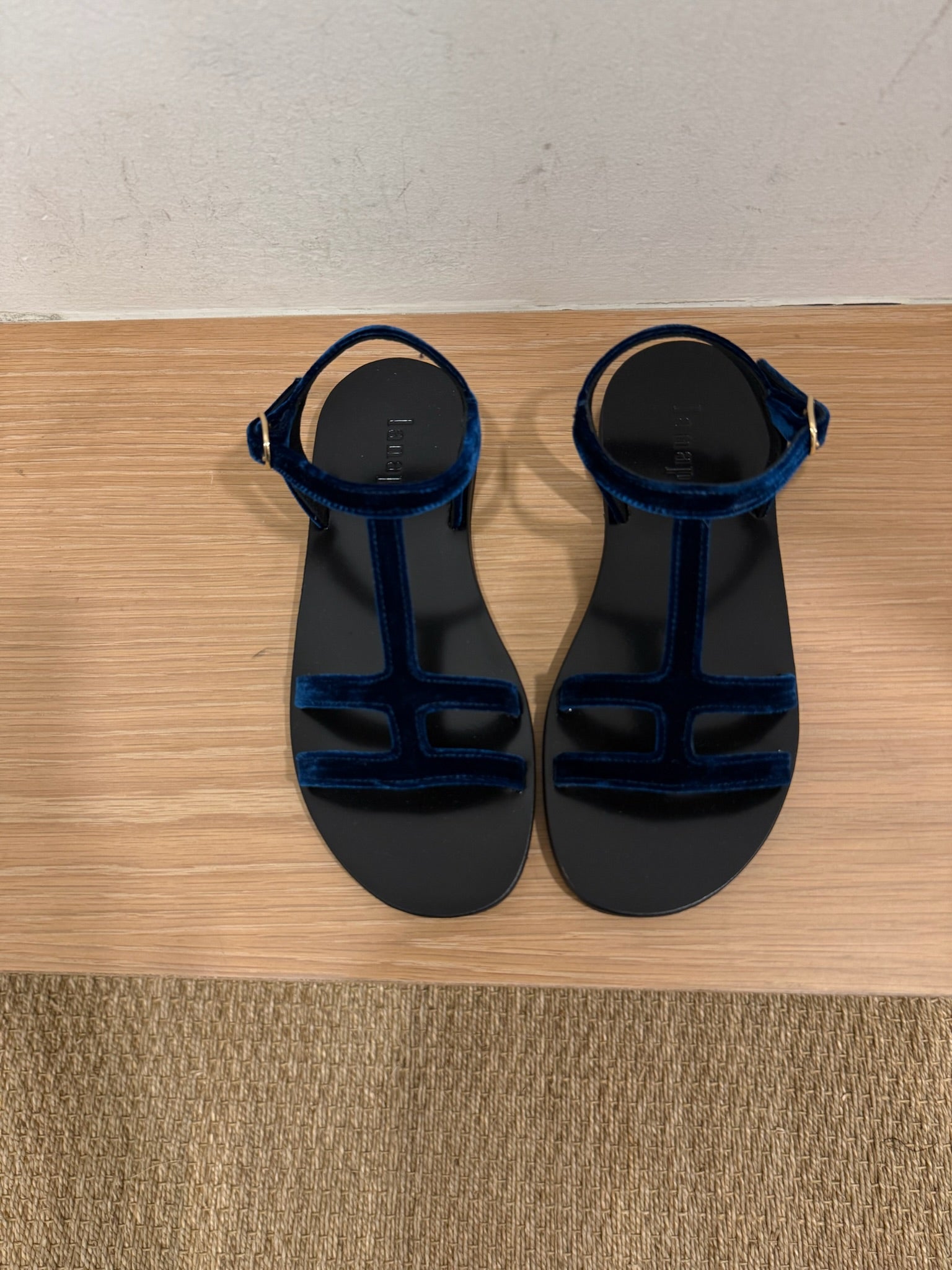 Blue suede sandals side by side on a bench in a dressing room. 
