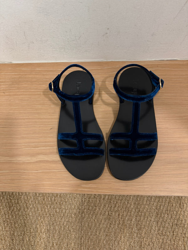 Blue suede sandals side by side on a bench in a dressing room. 