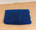 CLUTCH ON A WOOD BACKGROUND. THE CLUTCH IS TEXTURED AND IS THE COLOR blue
