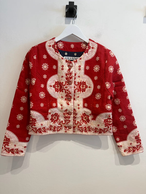 Red Bandana jacket hanging on w white hanger with a white wall background