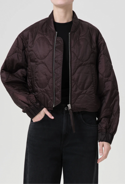 a model wearing a puffy bomber jacket with seam embellishments on a white background.