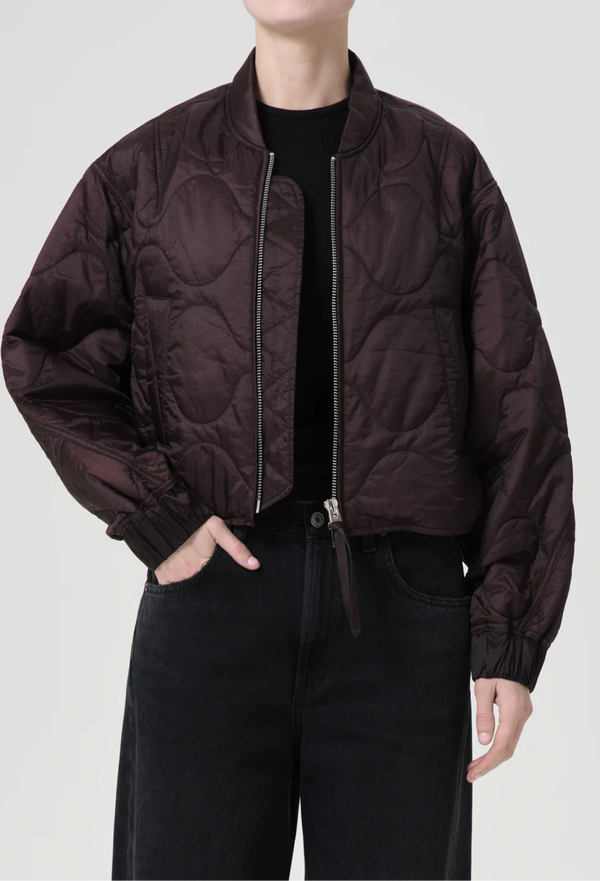 a model wearing a puffy bomber jacket with seam embellishments on a white background.