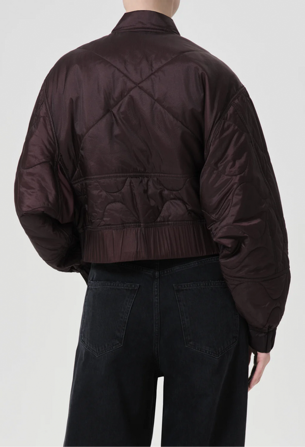 a model wearing a puffy bomber jacket with seam embellishments on a white background.