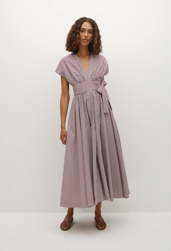 model wearing a burgundy stripe midi dress with a belted waist. white background