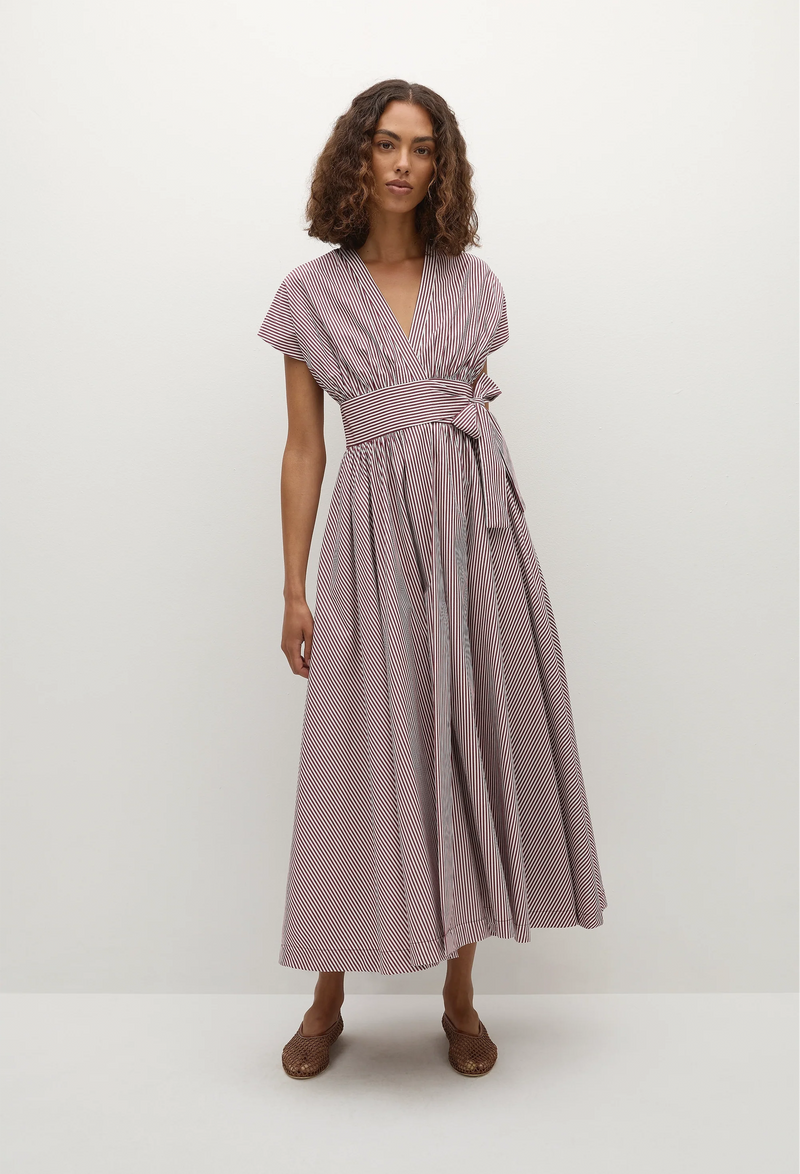 model wearing a burgundy stripe midi dress with a belted waist. white background
