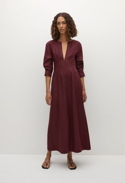 a model wearing a midi burgundy dress with 3/4 sleeves and a deep v-neck. white background.