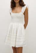a model wearing a white mini dress with a shirred bodice and cap sleeves. white background