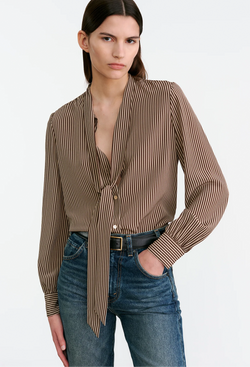 Woman wearing a brown striped blouse and blue jeans on a white background
