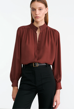Woman wearing a burgundy blouse and black pants on a white background