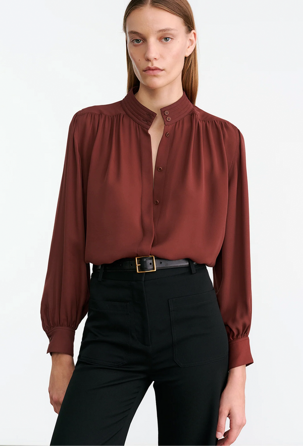 Woman wearing a burgundy blouse and black pants on a white background