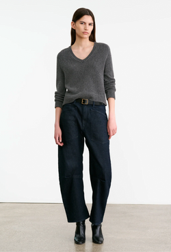 Woman wearing a gray sweater and dark pants on a white background