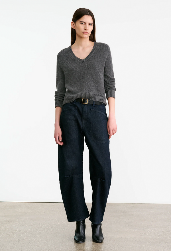 Woman wearing a gray sweater and dark pants on a white background