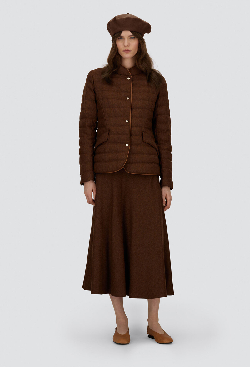 Woman wearing a brown quilted jacket and skirt on a white background