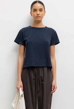 Person wearing a dark blue t-shirt and dark pants against a white background