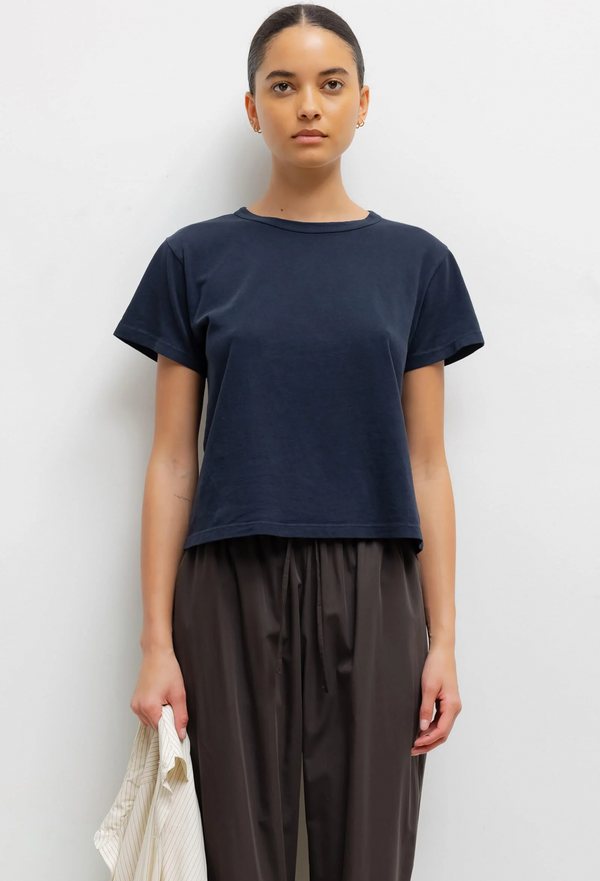 Person wearing a dark blue t-shirt and dark pants against a white background