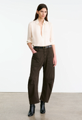 Woman wearing a white blouse and brown pants on a plain background