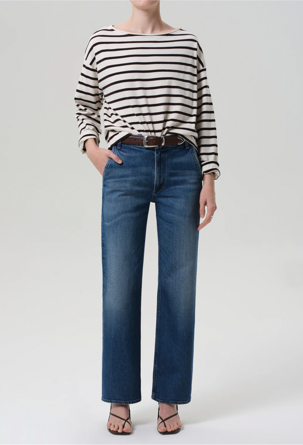 Person wearing a striped shirt and blue jeans on a plain background