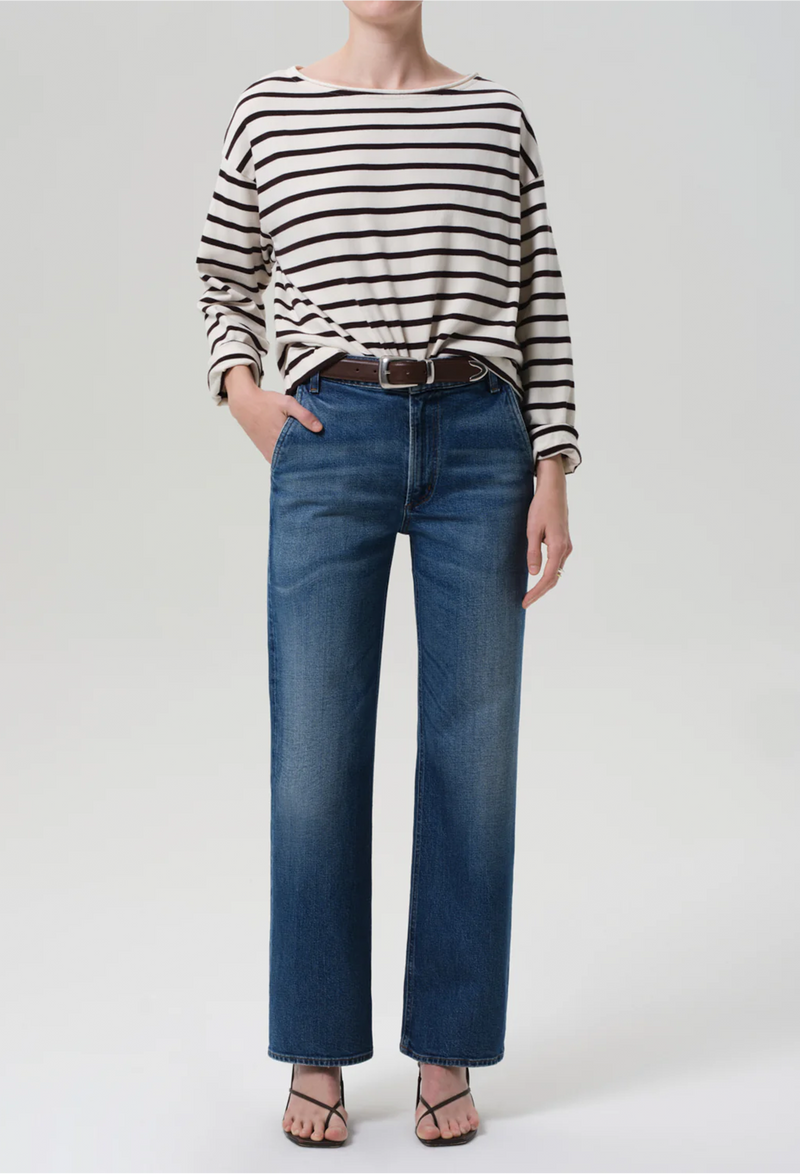 Person wearing a striped shirt and blue jeans on a plain background