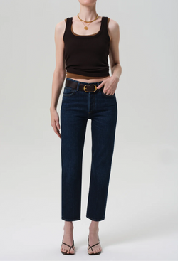 Person wearing a black tank top and dark blue jeans on a plain background