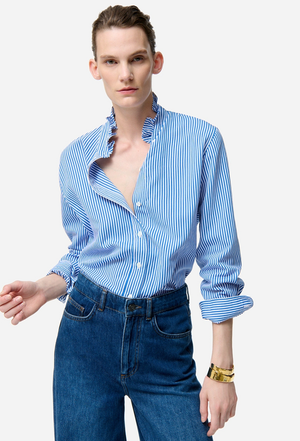 Person wearing a blue and white striped shirt with rolled-up sleeves and high-waisted jeans on a white background