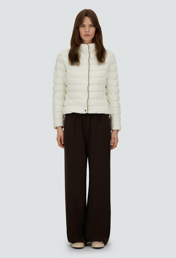Woman wearing a white puffer jacket and brown pants on a white background