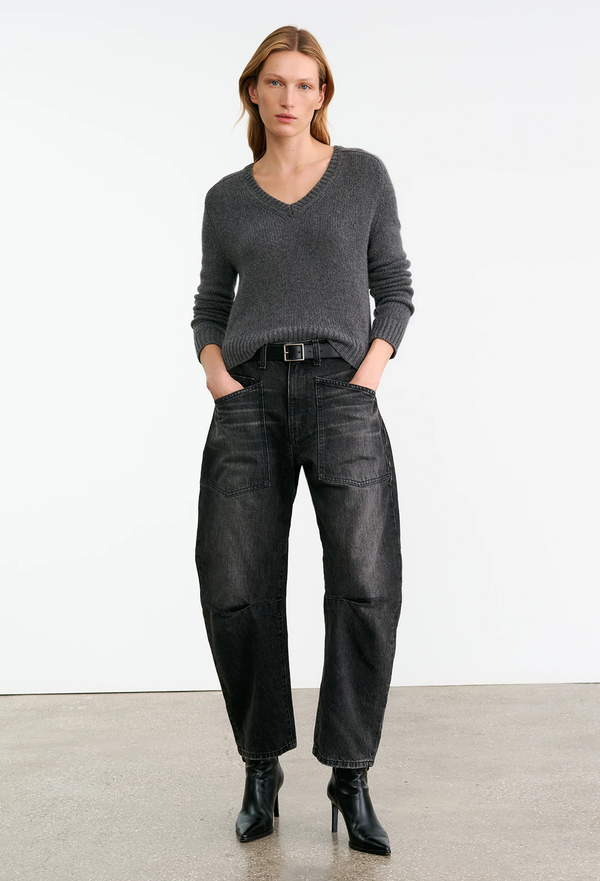 Woman wearing a gray sweater and black pants on a white background