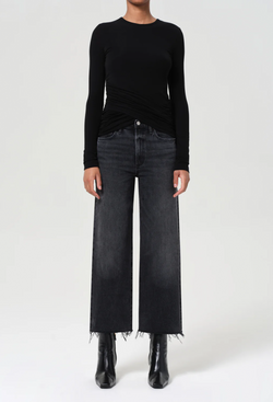 Person wearing a black long-sleeve top and black jeans on a white background