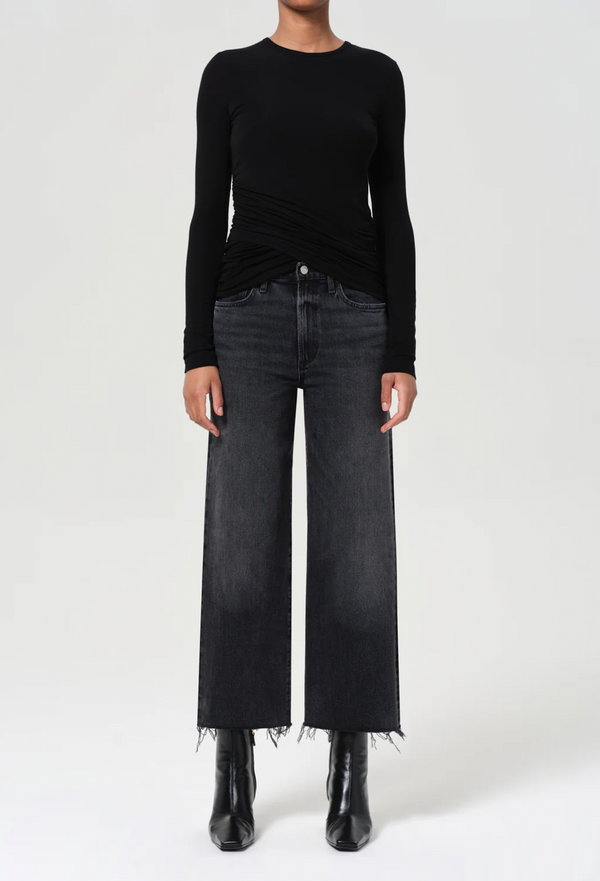 Person wearing a black long-sleeve top and black jeans on a white background