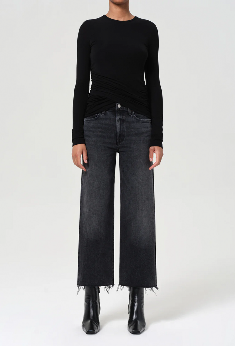 Person wearing a black long-sleeve top and black jeans on a white background
