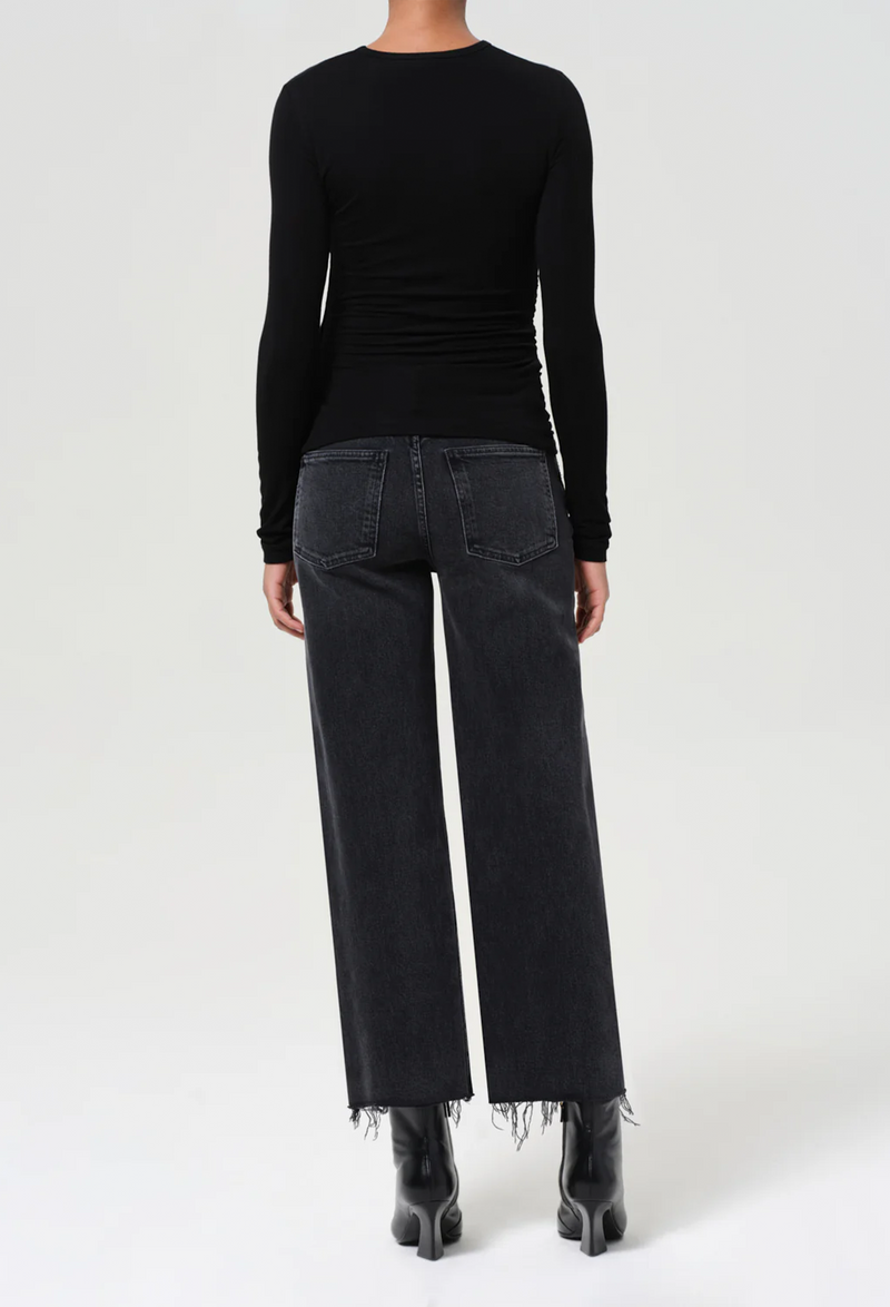 Person wearing a black long-sleeve top and black jeans on a white background