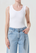 Person wearing a white tank top and light blue jeans on a plain background