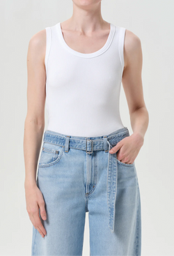 Person wearing a white tank top and light blue jeans on a plain background