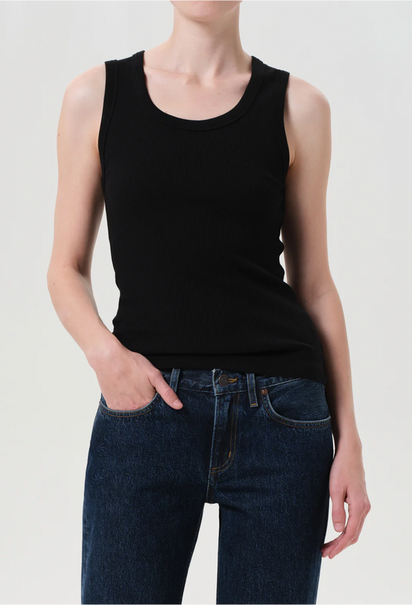 Person wearing a black tank top and blue jeans on a plain background