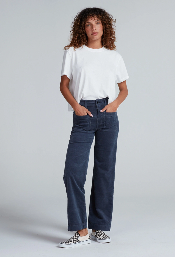 Woman wearing a white t-shirt and blue pants on a plain background