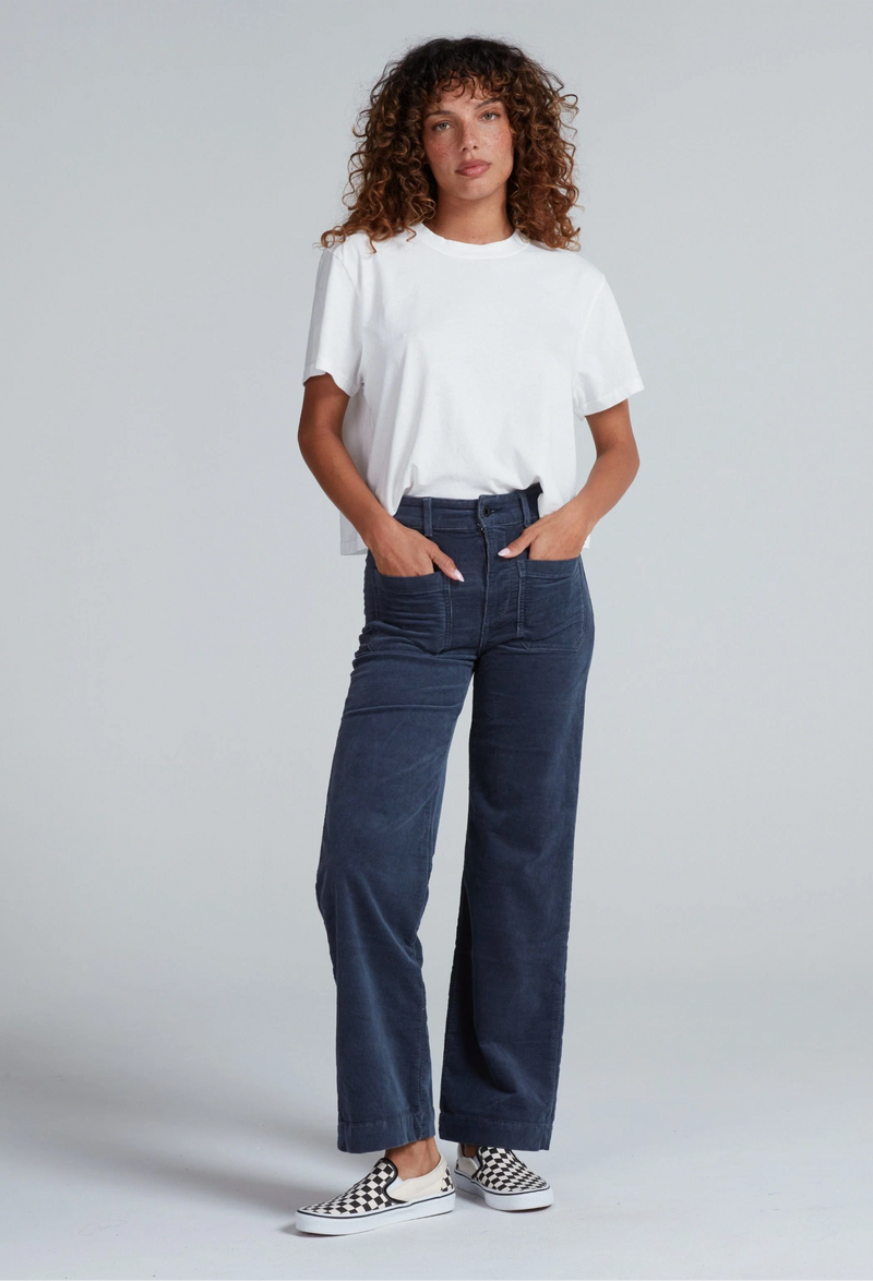 Woman wearing a white t-shirt and blue pants on a plain background