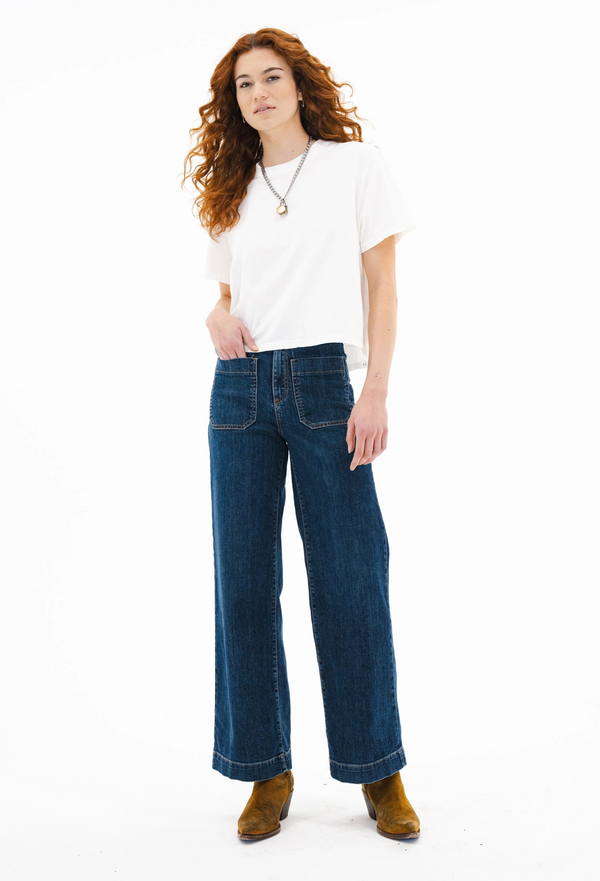 Woman wearing blue jeans and a white shirt on a white background