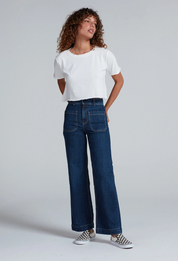 Woman wearing a white t-shirt and blue jeans on a plain background